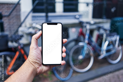 Man holding smartphone showing white blank screen at bike parking