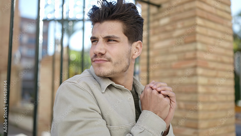 Obraz premium Young hispanic man rubbing hands for cold at street