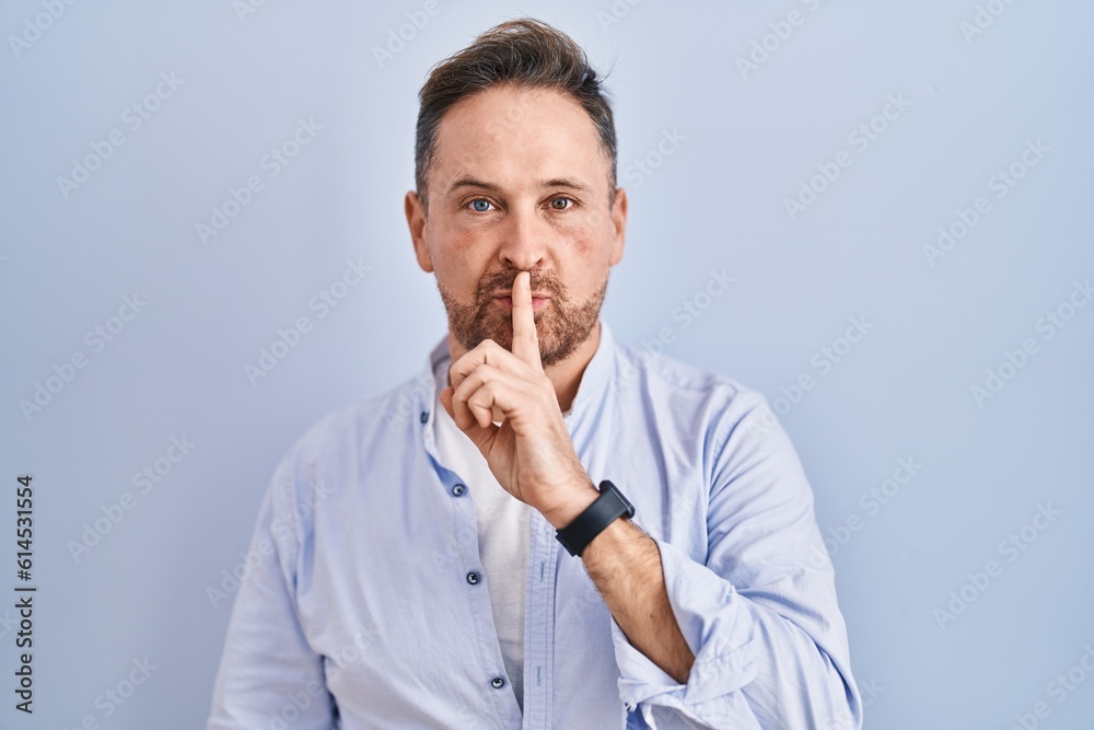 Middle age caucasian man standing over blue background asking to be quiet with finger on lips. silence and secret concept. Middle age caucasian man standing over blue background asking to be quiet with finger on lips. silence and secret concept.
