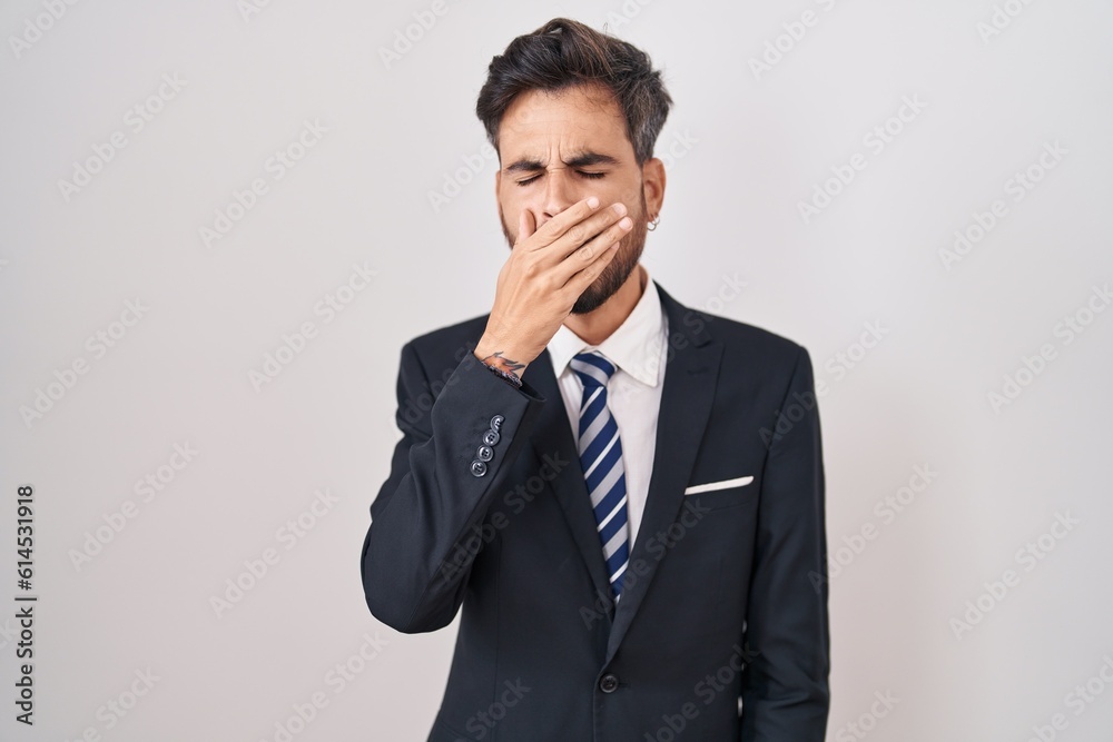 Young hispanic man with tattoos wearing business suit and tie bored yawning tired covering mouth with hand. restless and sleepiness. Young hispanic man with tattoos wearing business suit and tie bored yawning tired covering mouth with hand. restless and sleepiness.