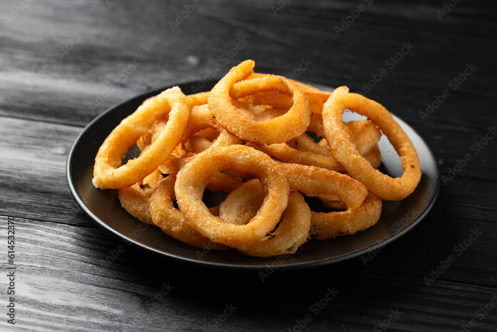 Crunchy Fried Battered onion rings on black plate Crunchy Fried Battered onion rings on black plate