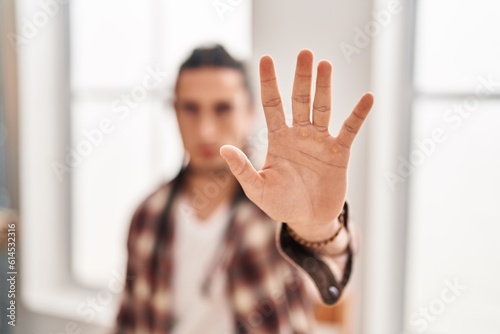 Young man ecommerce business worker doing stop gesture with hand at office