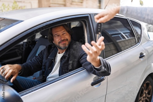 Middle age man smiling confident holding key of new car at street © Krakenimages.com