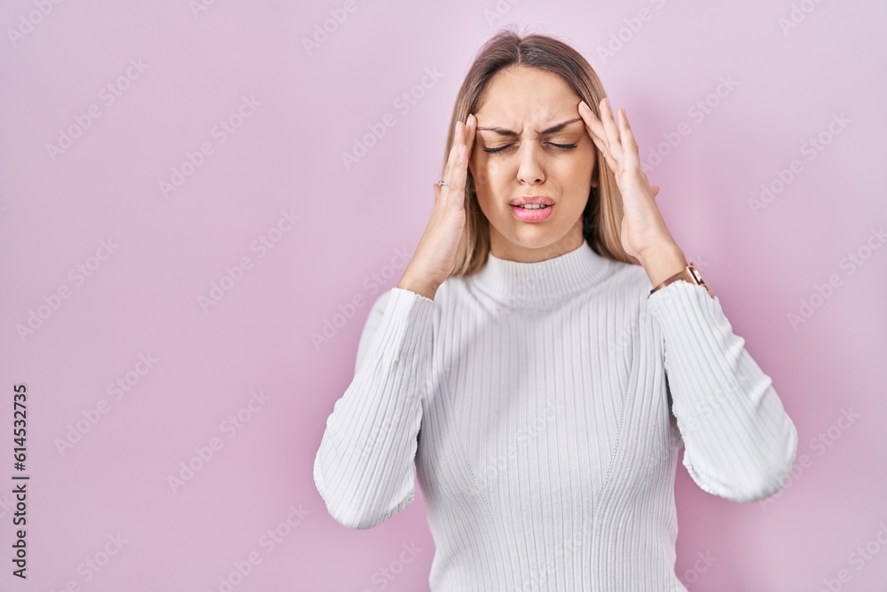 Young blonde woman wearing white sweater over pink background with hand on head for pain in head because stress. suffering migraine. Young blonde woman wearing white sweater over pink background with hand on head for pain in head because stress. suffering migraine.
