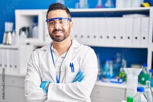 Young hispanic man scientist smiling confident with arms crossed gesture at laboratory
