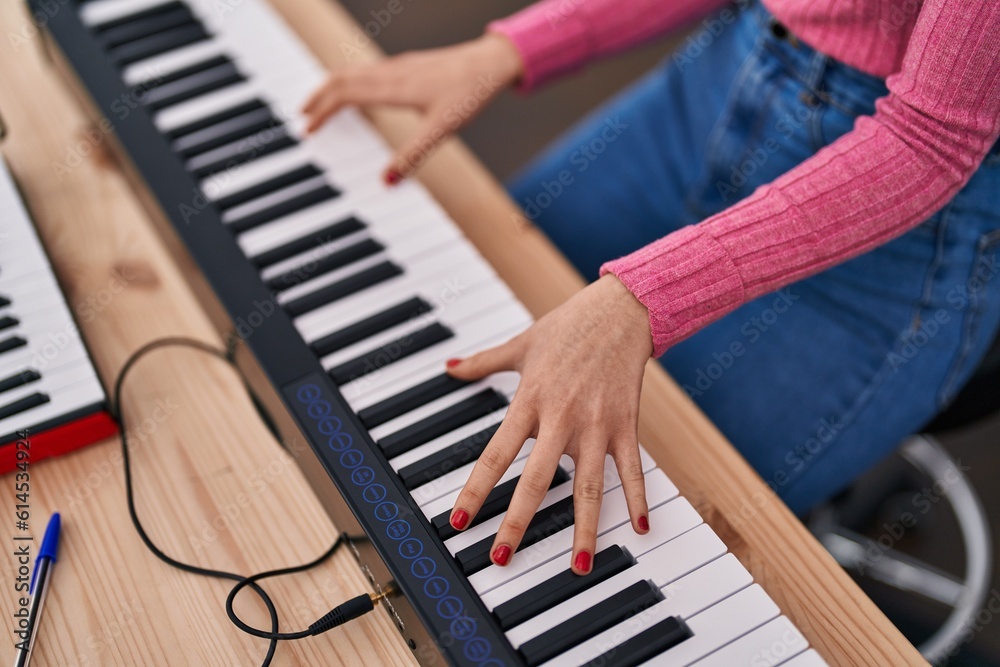 Obraz premium Young caucasian woman musician playing piano at music studio