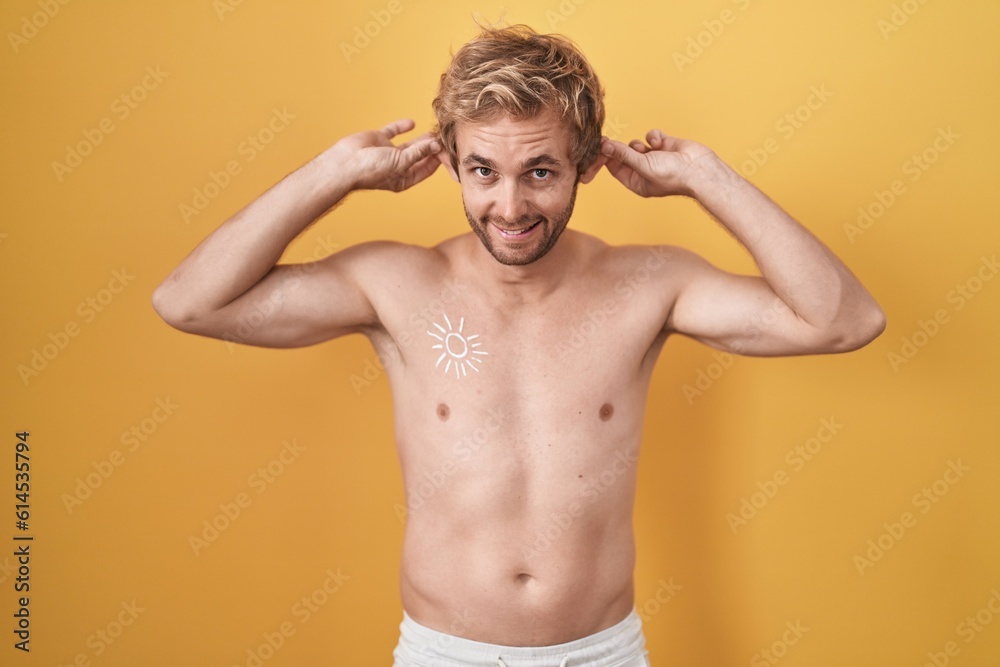 Caucasian man standing shirtless wearing sun screen smiling pulling ears with fingers, funny gesture. audition problem