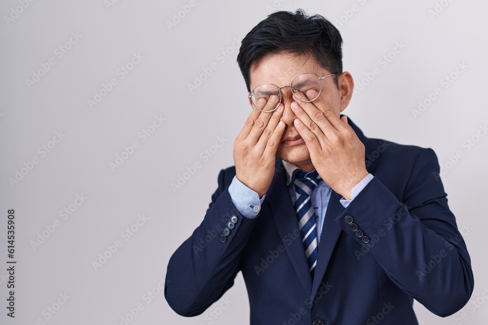 Young asian man wearing business suit and tie rubbing eyes for fatigue and headache, sleepy and tired expression. vision problem Young asian man wearing business suit and tie rubbing eyes for fatigue and headache, sleepy and tired expression. vision problem
