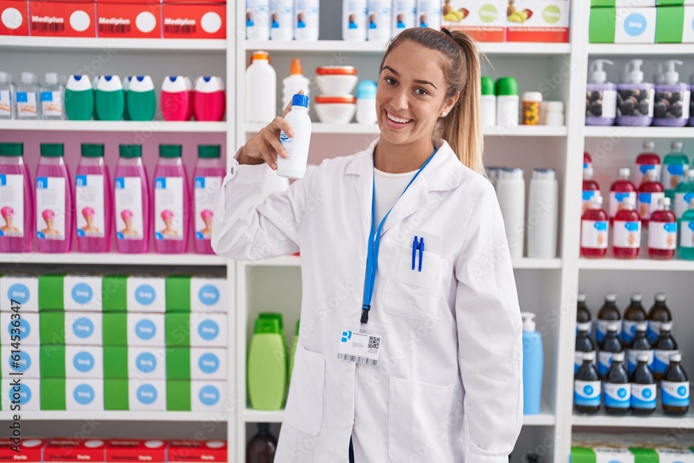 Young beautiful hispanic woman pharmacist smiling confident holding bottle at pharmacy