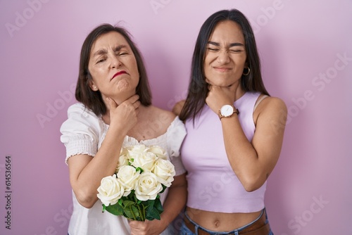 Hispanic mother and daughter holding bouquet of white flowers touching painful neck, sore throat for flu, clod and infection