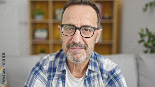 Middle age man sitting on sofa with relaxed expression at home