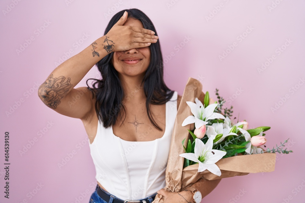 Brunette woman holding bouquet of white flowers smiling and laughing with hand on face covering eyes for surprise. blind concept. Brunette woman holding bouquet of white flowers smiling and laughing with hand on face covering eyes for surprise. blind concept.