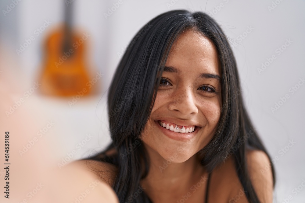 Young hispanic woman make selfie by camera sitting on bed at bedroom Young hispanic woman make selfie by camera sitting on bed at bedroom
