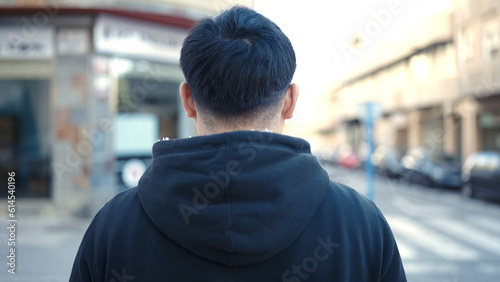Young chinese man standing on back view at street
