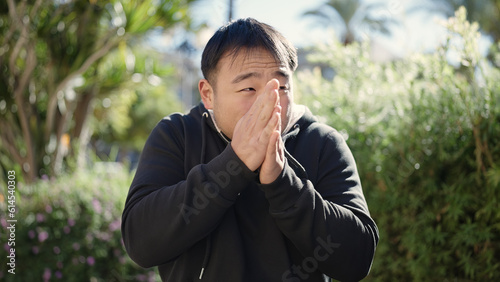 Young chinese man rubbing hands for cold at park