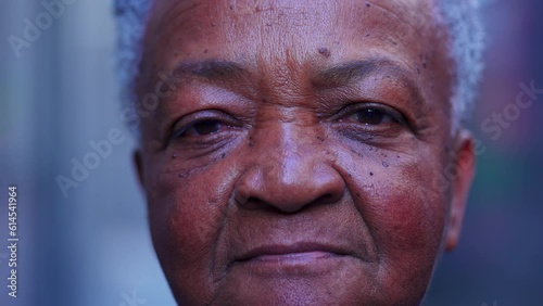 Macro close-up of a black senior Brazilian woman looking at camera in neutral serious expression. Portrait of an African American elderly lady