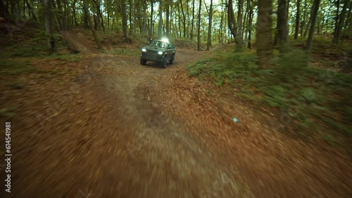 Aerial shot of modern armored military pickup truck riding through green forest on summertime outdoor. Footage of military vehicle. Nature, trees. War concept