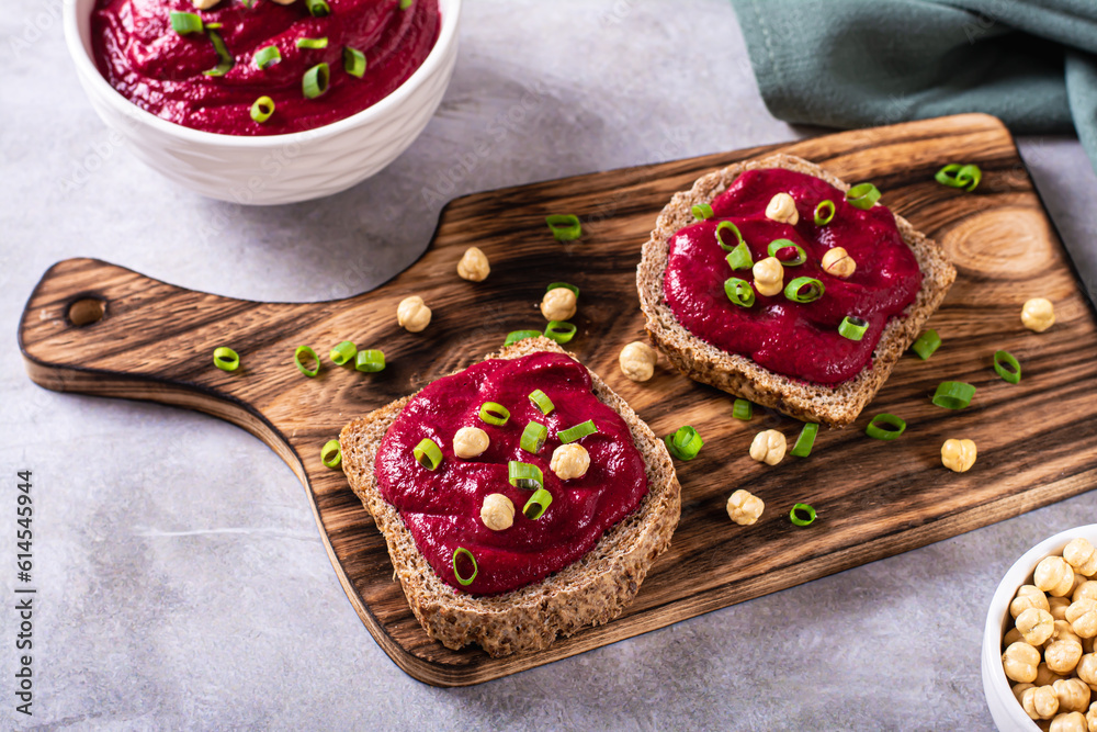 Appetizing rye bread bruschettas with beetroot hummus and chives on a cutting board
