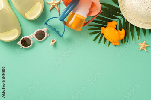 Blissful summer vacation with children by the seaside. Above view snapshot of sand toys for kids, panama, slippers, sunglasses, palm tree and starfish on isolated teal background with copyspace