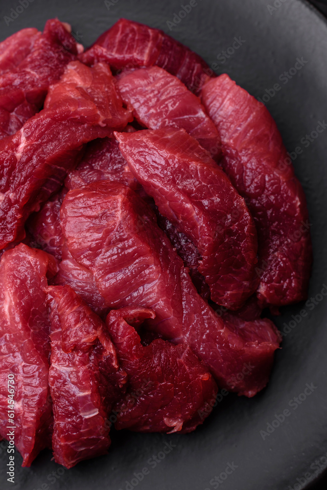 Juicy raw beef with spices, salt and herbs on a dark concrete background Juicy raw beef with spices, salt and herbs on a dark concrete background