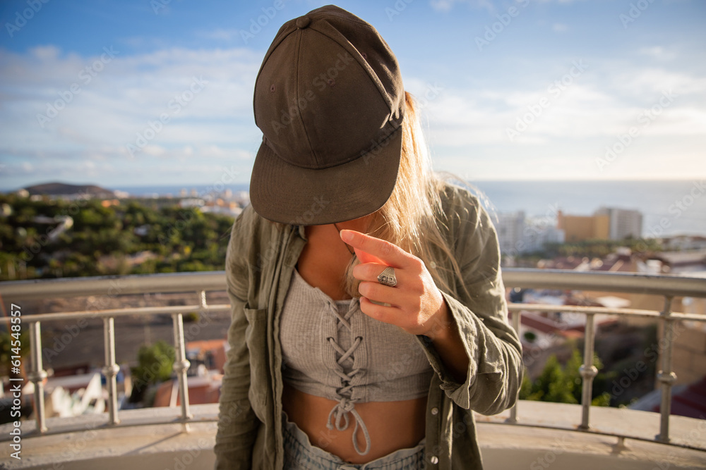 Hip hop girl wears a cap and keeps her face down while on the balcony
