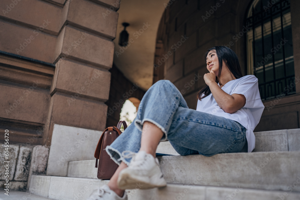 Young Japanese woman sitting on the stairs of office building