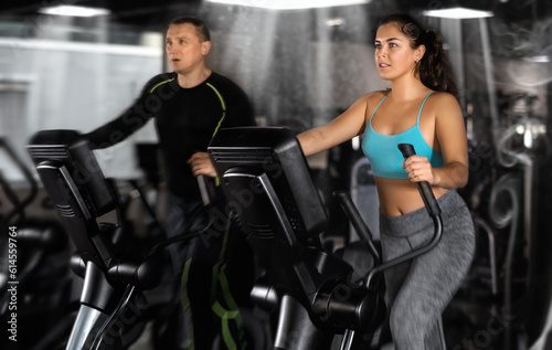 Athletic young woman exercising on an elliptical trainer in the gym
