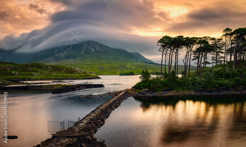 Schilderij op canvas Dramatic cloudy sunrise lakeside landscape scenery of twelve pines island reflec