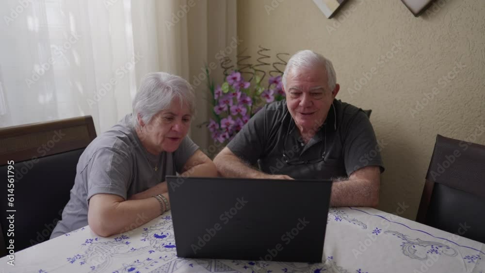 Seniors communicating via video conference with family member on computer laptop, older husband and wife waving hello and sending kisses in front of screen Seniors communicating via video conference with family member on computer laptop, older husband and wife waving hello and sending kisses in front of screen