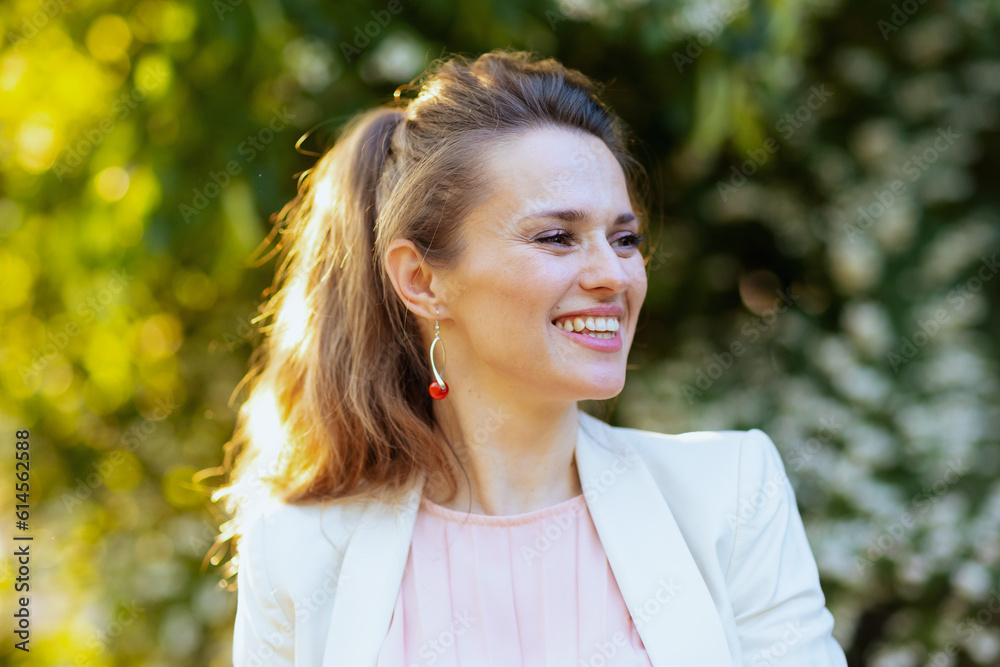 smiling trendy woman in pink dress and white jacket in city smiling trendy woman in pink dress and white jacket in city
