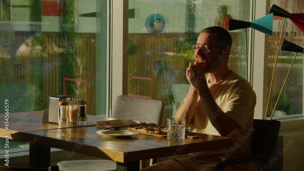 A bearded man with great appetite eats pizza and enjoys it in a restaurant A bearded man with great appetite eats pizza and enjoys it in a restaurant