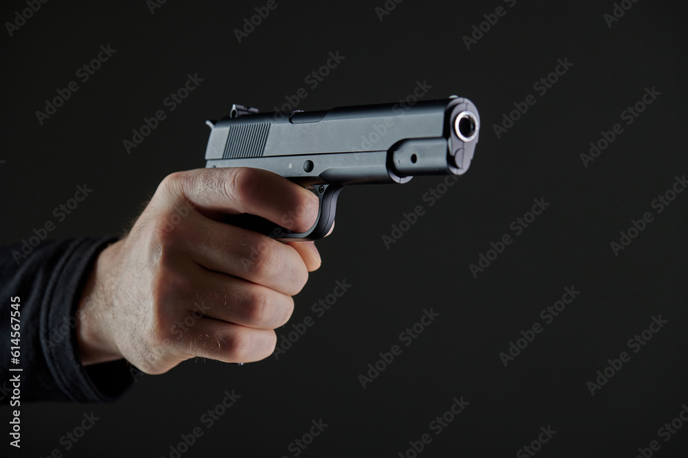 Male hand holding a gun on black background . A gun in a man's hand. defense or attack murderer or armed robber, First person view of a pistol. Male hand holding a gun on black background . A gun in a man's hand. defense or attack murderer or armed robber, First person view of a pistol.