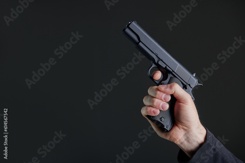 Male hand holding a gun on black background . A gun in a man's hand. defense or attack murderer or armed robber, First person view of a pistol.