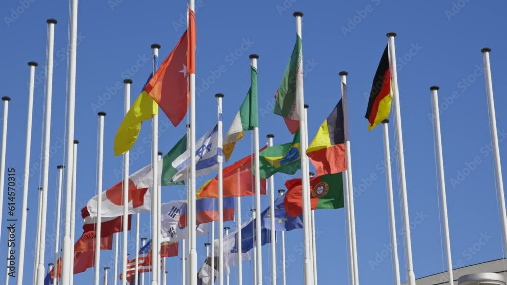 Flags of different countries on the flagpole at the background of blue clear sky Flags of different countries on the flagpole at the background of blue clear sky
