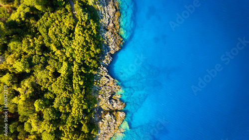 Fototapeta Naklejka Na Ścianę i Meble -  View from the air on the waves and rocks. Sea relaxation and travel. The forest near the sea. Azure water on the sea. A bright sunny day during a summer vacation.