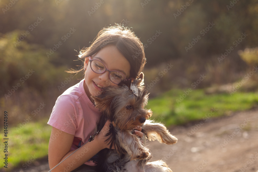 Little girl with her Yorkshire Terrier dog in a park at sunset Little girl with her Yorkshire Terrier dog in a park at sunset
