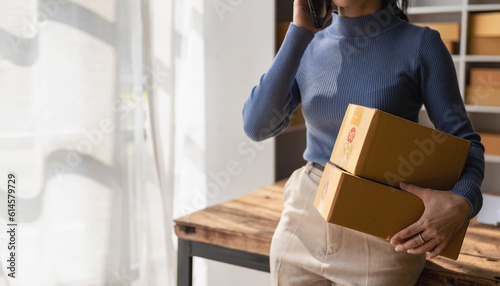 Remote photo business from home Asian woman preparing package delivery box for online shopping Young start-up small SME business owner at home orders online with parcel delivery