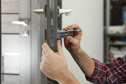 Handyman changing core of door lock indoors, closeup