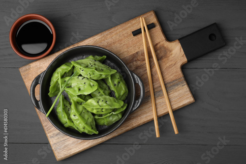 Delicious green dumplings (gyozas) served on grey wooden table, flat lay