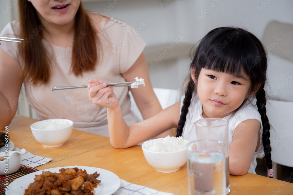 Happiness asian family mother and daughter eating food in kitchen together at home, parent and kid sitting dining in living room, bonding and relation, lifestyles and nutrition concept. Happiness asian family mother and daughter eating food in kitchen together at home, parent and kid sitting dining in living room, bonding and relation, lifestyles and nutrition concept.