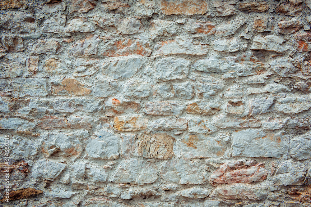 The background of an old brick wall covered with white plaster close up. Texture of white orange brick, light brick background