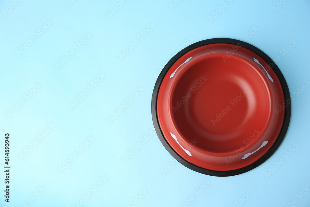 Empty red feeding bowl on light blue background, top view. Space for text