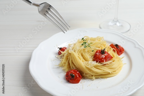 Eating tasty capellini with tomatoes and cheese at white wooden table, closeup. Exquisite presentation of pasta dish