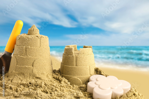 Sand castles with toys on ocean beach, closeup. Outdoor play © New Africa