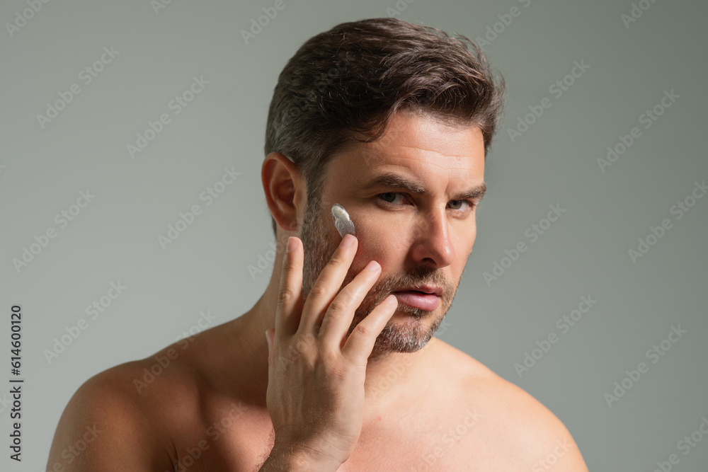 Fototapeta premium Sexy bearded man care of skin. Unshaven man with bristle and perfect skin. Male beauty and skincare concept. Man cosmetic, skin treatment. Morning hygiene. Mens cosmetics and spa and wellness.