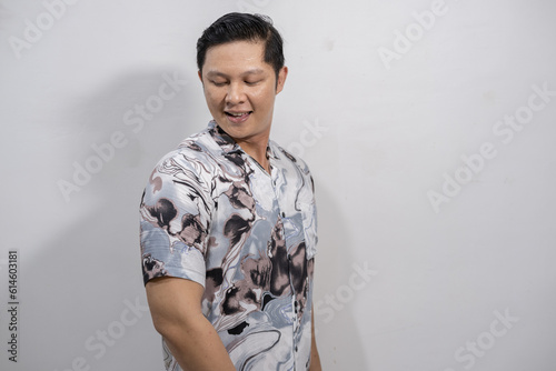 Young Asian man wearing a vintage black and gray patterned shirt looking happy and confident while showing off the shirt he is wearing photo