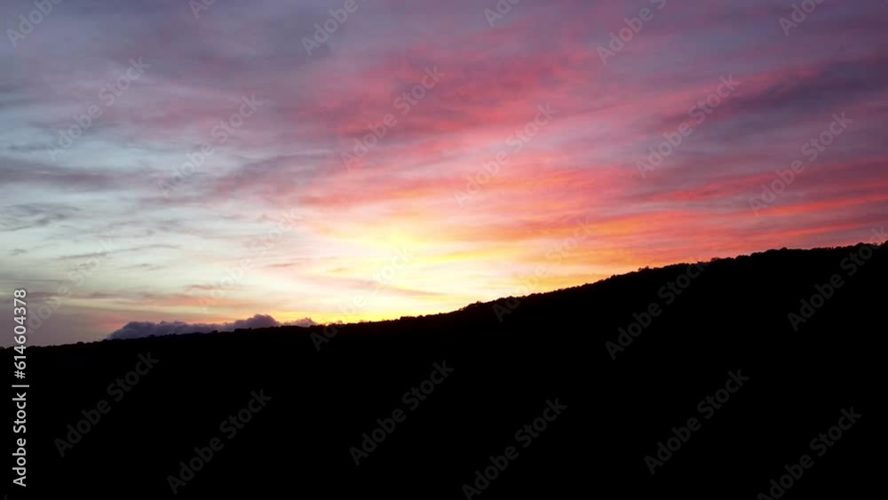 Aerial view of colourful pink cloudy sky during dramatic sunset with silhouetted mountain landscape in the remote wilderness Aerial view of colourful pink cloudy sky during dramatic sunset with silhouetted mountain landscape in the remote wilderness