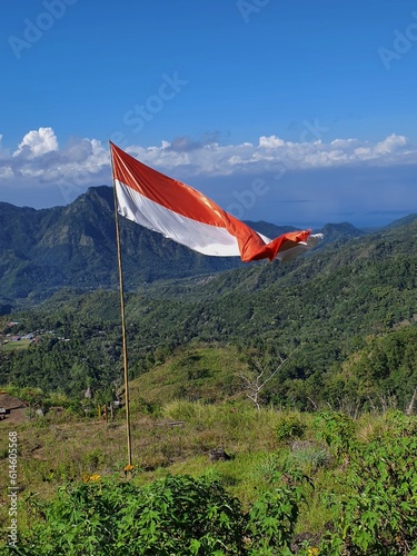 An image of the Indonesian national flag Sang Merah Putih fluttering on the slopes of Mount Inerie in the island of Flores, Indonesia photo