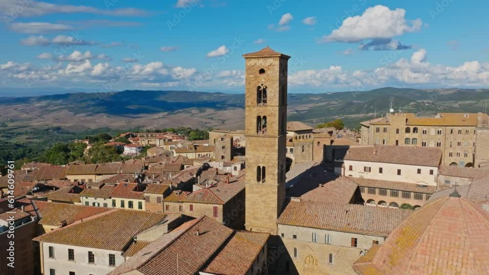 Aerial over rooftops towards one of the Towers of the Palace of the Priors, Palazzo dei Priori, Volterra, Province of Siena, Italy. Drone dolly forward and orbit shot