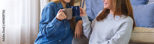 Closeup image of a young couple women clinking and drinking coffee together